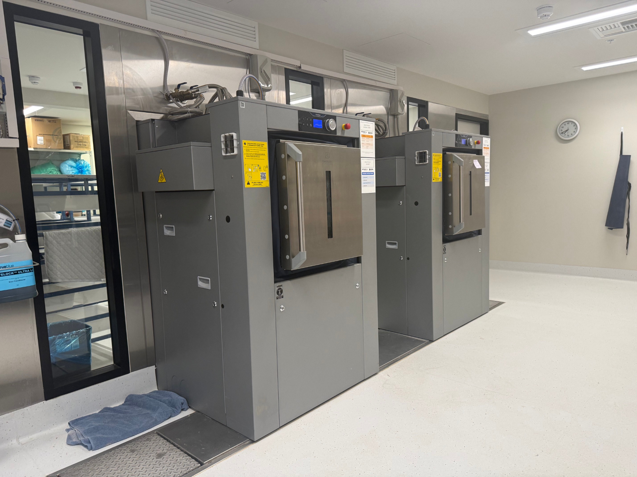 Two installed barrier washer extractors set into the laundry wall line