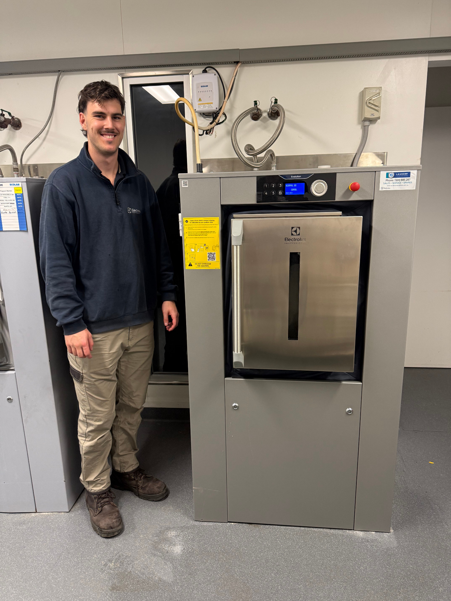 Technician standing beside a newly installed barrier washer extractor
