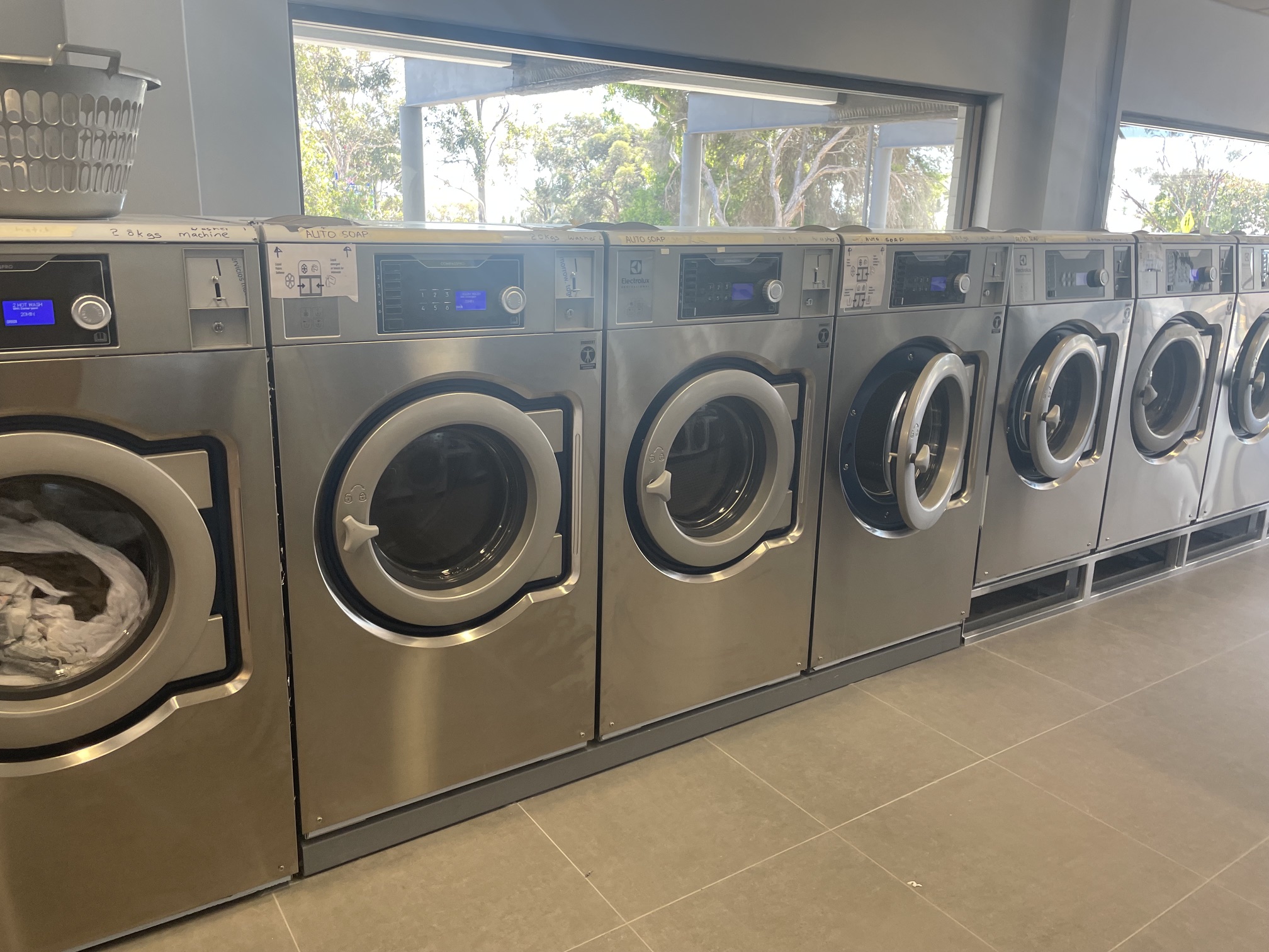 Row of newly installed commercial washer extractors in a self-service laundromat