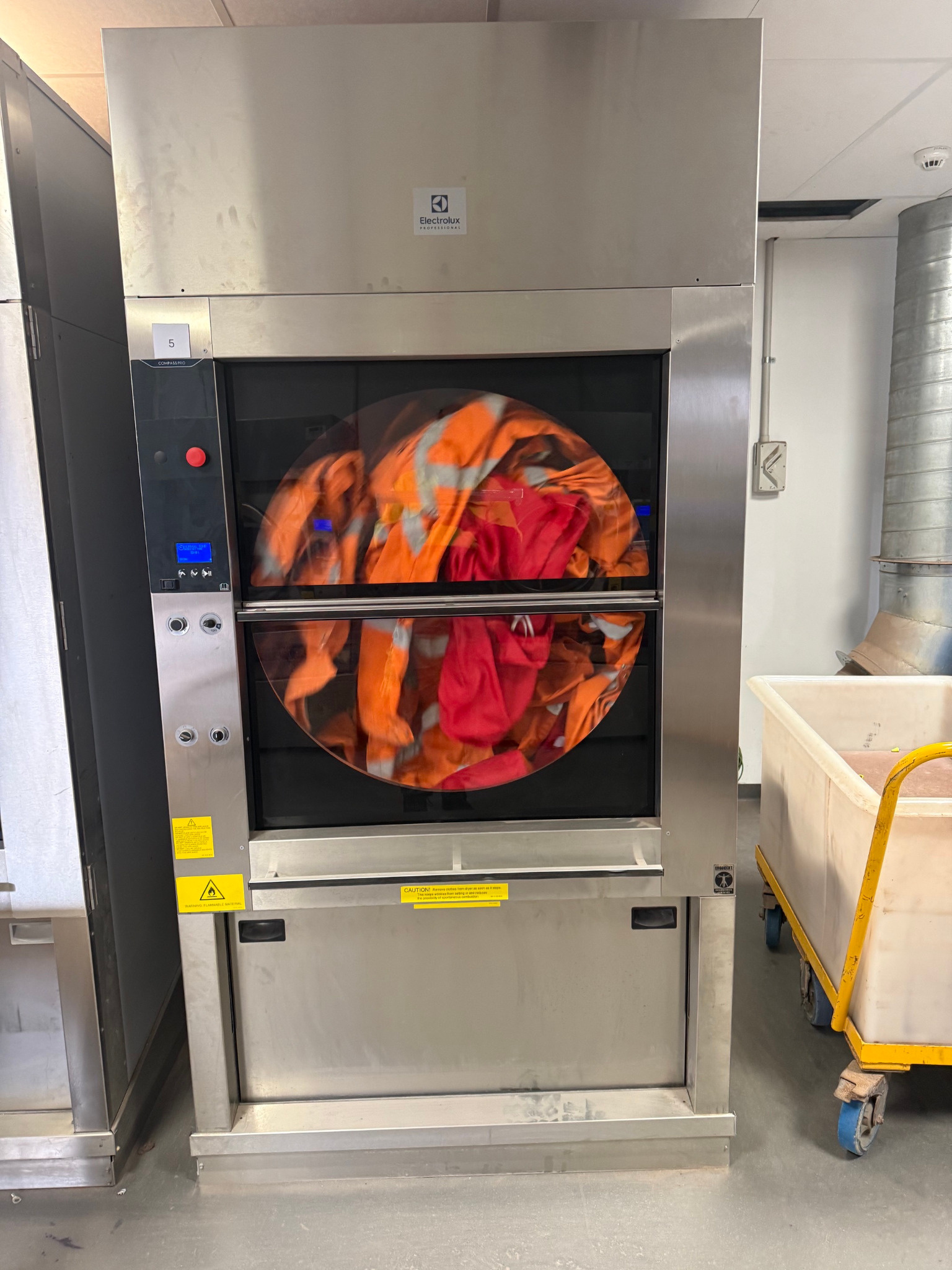 Commercial tumble dryer processing high-visibility workwear
