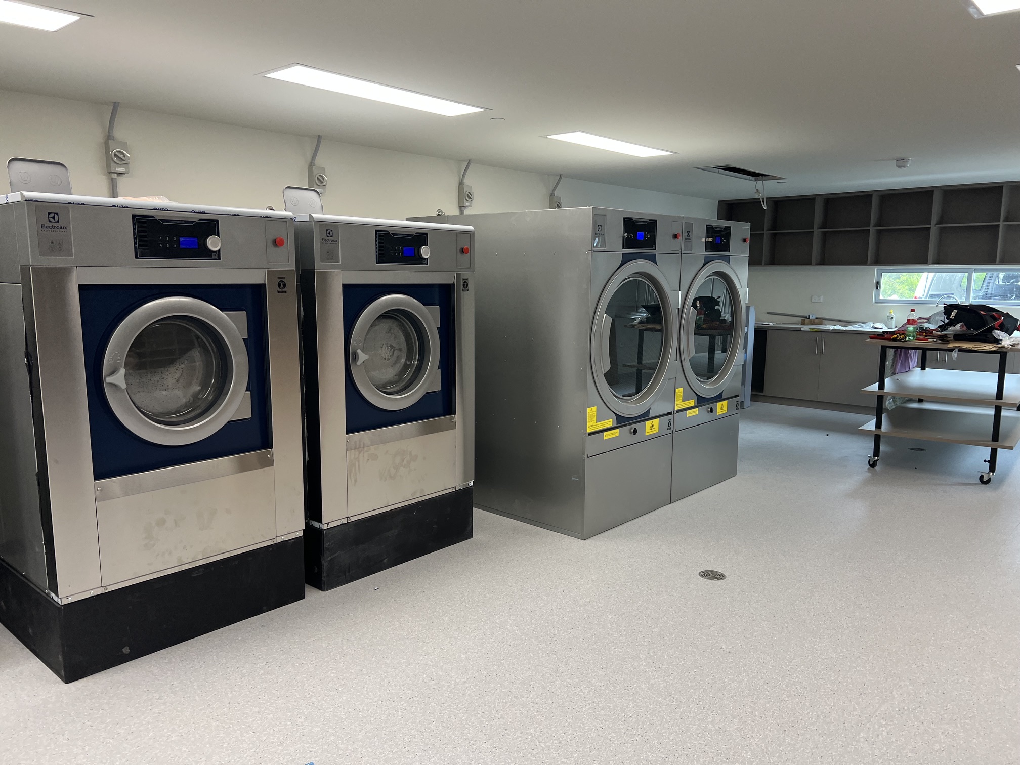 Commercial washer extractors and tumble dryers installed in a spacious hotel laundry
