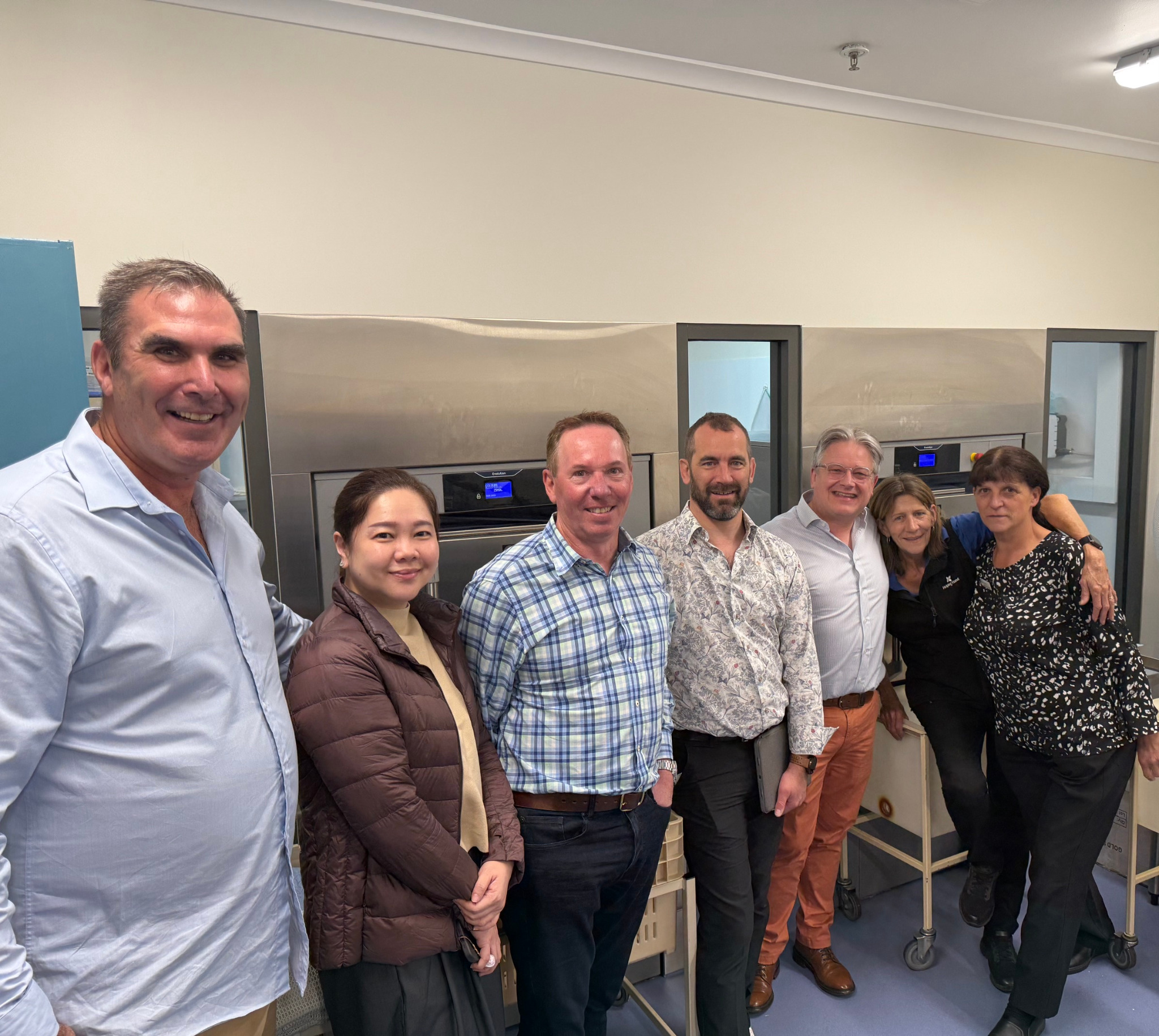 Laundry specialists and factory representatives standing beside newly installed barrier washers