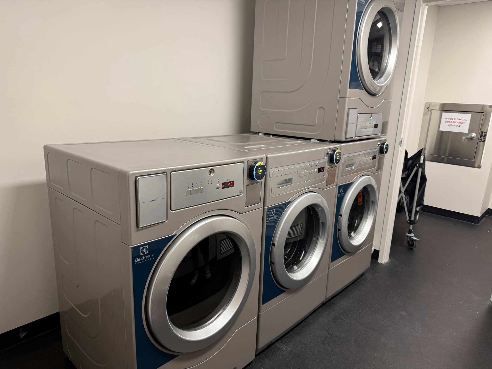 Stacked commercial washers and dryers installed in a compact student accommodation laundry